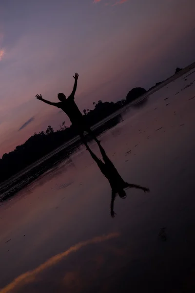 Homme sur la plage avec reflet dans l'eau au coucher du soleil . — Photo