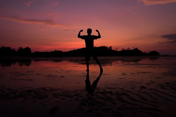 Homme sur la plage avec reflet dans l'eau au coucher du soleil . — Photo