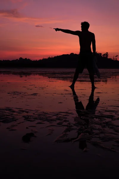 Homme sur la plage avec reflet dans l'eau au coucher du soleil . — Photo