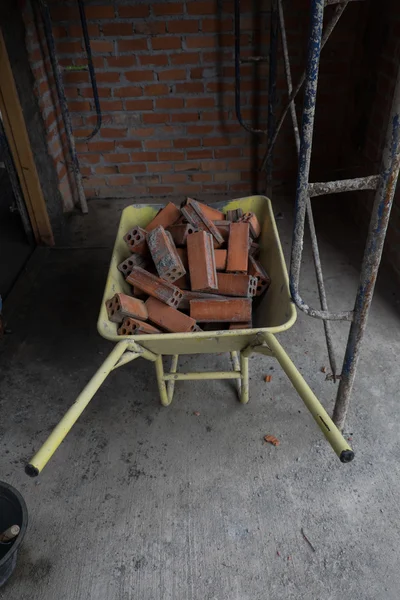 Красный кирпич в строительной тележке — стоковое фото