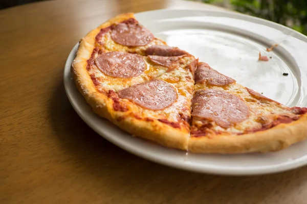 Sliced salami pizza on a white plate — Stock Photo, Image