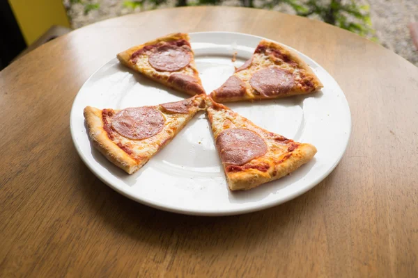 Sliced salami pizza on a white plate — Stock Photo, Image