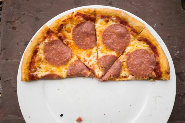 Sliced salami pizza on a white plate — Stock Photo, Image