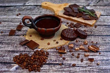 Kahverengi ahşap arka planda bir fincan kahve, tahıl ve çikolata.