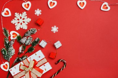 Yeni yıl kompozisyonu. Noel hediyeleri, çam dalları, kırmızı arka planda oyuncaklar. Düz yatış, üst görünüm