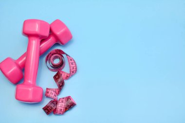 Pembe halterler 2.0 kilogram ve mavi arka planda pembe mezura, fotokopi alanı, kilo verme konsepti. Üst görünüm