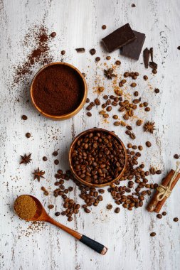 Dikey kompozisyon. Kahve çekirdekleri ve öğütülmüş kahve, çikolata, ahşap arka planda tarçın çubukları. Üst görünüm