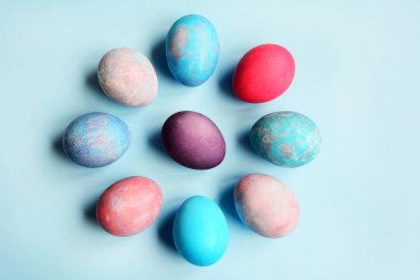 Easter concept. Multi-colored colored eggs lie in a circle on a blue background. Layout, top view