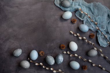 Düz konum, kopyalama alanı. Gri bir arka planda paskalya kompozisyonu. Mavi, mermer ve gri yumurtalar, söğüt dalları ve bir peçete. Yukarıdan görüntüle