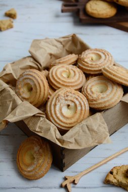 Hafif arka planda ahşap bir kutuda kurabiyelerin yakın çekimi. Dikey.