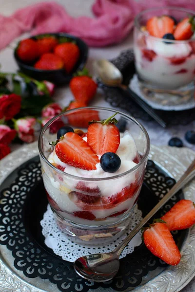 Close-up of a glass with curd dessert with berries - strawberries, blueberries and cookies on metal plates on a gray background. Vertical view — 스톡 사진