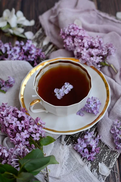 Vista vertical de uma xícara de chá com pétalas de lilás. Fechar.. — Fotografia de Stock