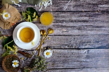 White cup with herbal tea, honey, linden, thyme, on a rustic wooden background. Top view, copy space.