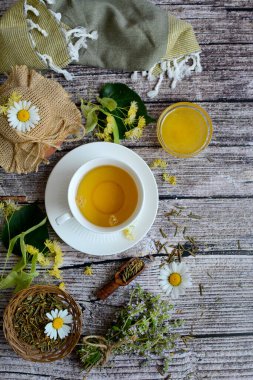 Vertical view of a cup of herbal tea, linden herb, thyme, honey on a rustic wooden background. View from above