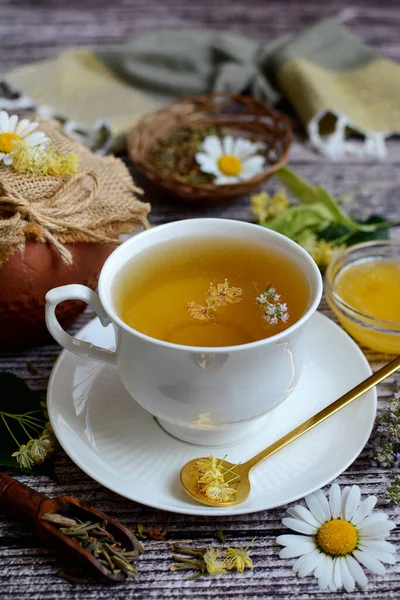 Close-up white cup with chamomile tea and honey on a wooden background. Vertical composition