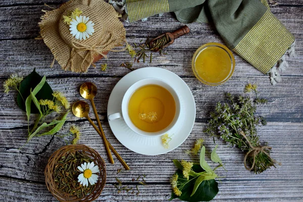 Composition with herbs. Chamomile tea, linden, thyme, honey and dried herbs on a wooden table. View from above.