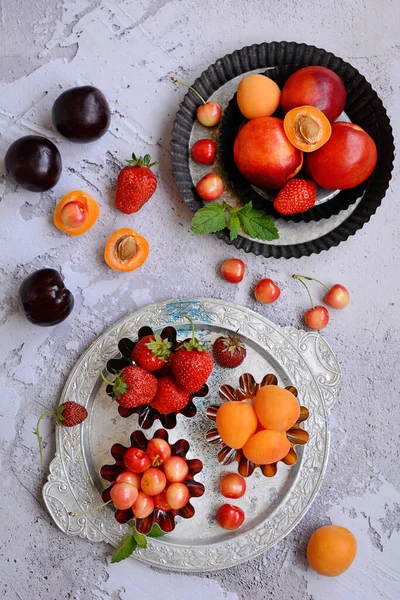 Composição vertical. Bagas maduras suculentas e frutas em placas de metal em um fundo texturizado cinza. Vista de cima. — Fotografia de Stock