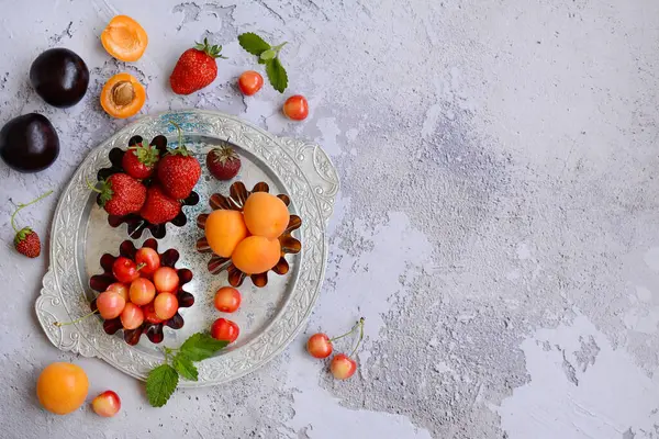 Layout de frutas suculentas e bagas em uma placa de metal em um fundo texturizado cinza. Espaço de cópia, vista superior — Fotografia de Stock