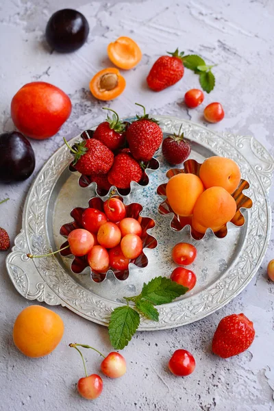 Bagas maduras suculentas e frutos em uma chapa metálica em um contexto cinza. Vista de cima. — Fotografia de Stock