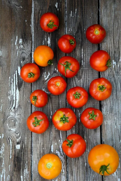 Diseño vertical de tomates maduros rojos y amarillos sobre un fondo de madera con textura gris. Vista desde arriba — Foto de Stock