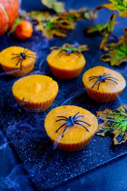 Kabak keklerinin dikey görüntüsü, dekoratif örümcekler ve arka planda örümcek ağları. Cadılar Bayramı Dekorasyonu.
