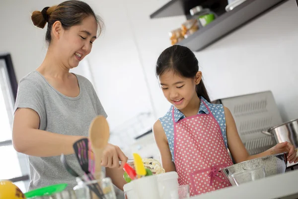 Little Asian cute chef cooking a bakery in kitchen with mother