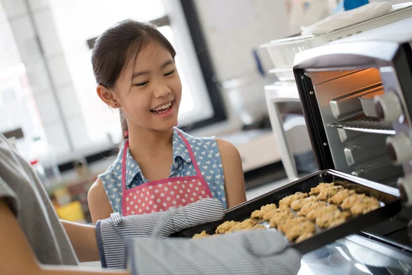 Happy little Asian cute chef looking cookies from oven — Stock Photo, Image