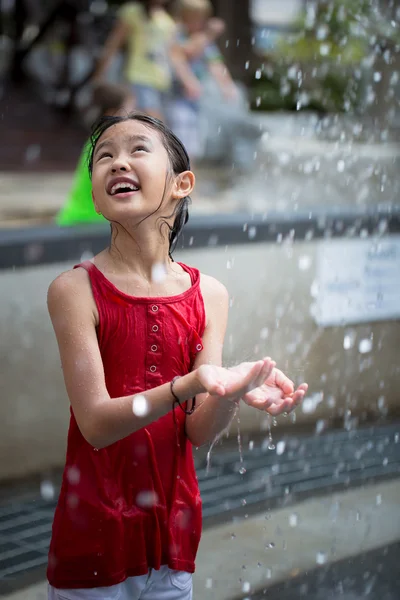 Asiatische Mädchen spielen mit Wasserfontäne im Wasserpark — Stockfoto