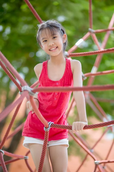 Des enfants mignons. Asiatique fille escalade dans une corde aire de jeux structure à aventure parc — Photo