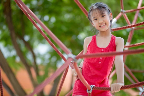 Des enfants mignons. Asiatique fille escalade dans une corde aire de jeux structure à aventure parc — Photo