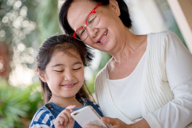 Cep telefonunuzun ve büyükannesi ile birlikte küçük Asyalı kız