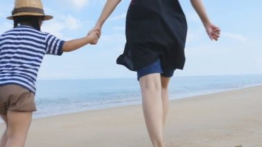 Ağır çekim mutlu Asya anne ve kızı birlikte kum plajı üzerinde çalışan