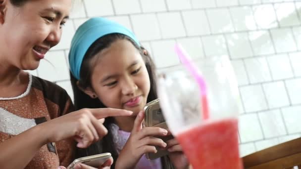 Pequeña madre asiática y su hija jugando en el teléfono inteligente, disparo en cámara lenta — Vídeo de stock