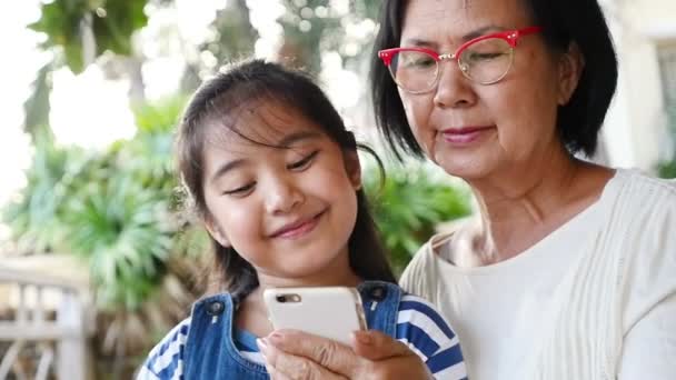 Malá Asiatka pomocí smartphonu s babičkou, šťastný rodinný koncept, zpomalené zastřelil.