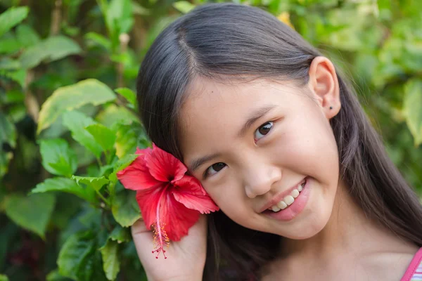 Petite fille asiatique souriant avec rose chinoise dans le jardin — Photo