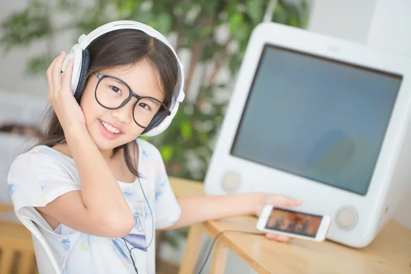 Attraente ragazza asiatica ascoltare musica su smartphone con cuffie nella stanza — Foto Stock