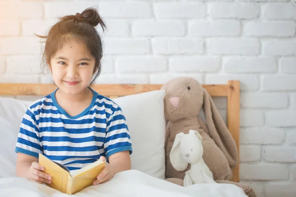 Menina asiática feliz ler livro história na cama — Fotografia de Stock