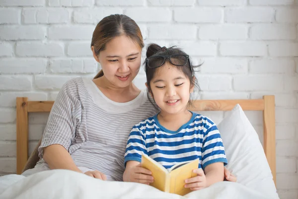 Happy Asian girl reading story book with her mother together — Stock Photo, Image