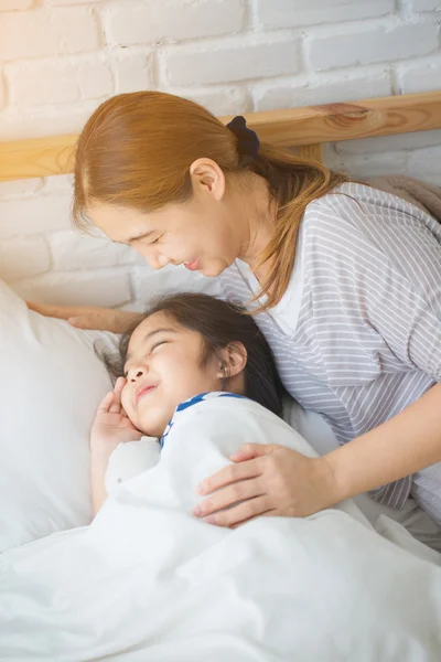 Asiatiska mamma vaknade dottern på sängen på morgonen — Stockfoto