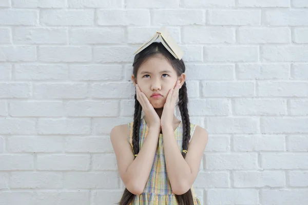 Engraçado retrato de ação da menina asiática lendo livro de história na parede de tijolo branco — Fotografia de Stock