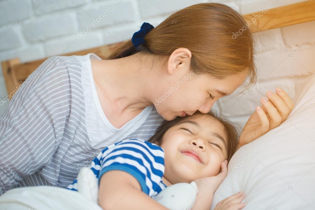 Asian Mother Kissing Her Daughter Goodnight On The Bed Stock Photo By