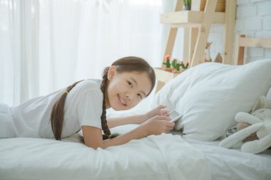 Mutlu güzel Asyalı kız yatakta yatarken tablet kullanma