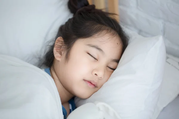 Μικρό ασιατικό κορίτσι αγκαλιάζει την κούκλα και να κοιμάται στο κρεβάτι — Φωτογραφία Αρχείου