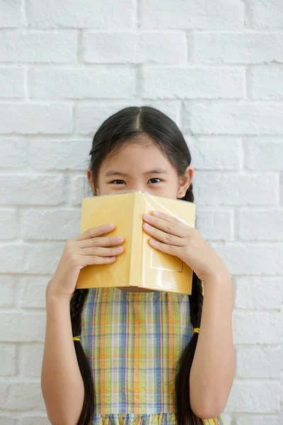白いレンガの壁に物語の本を読んで幸せなアジアの女の子 — ストック写真