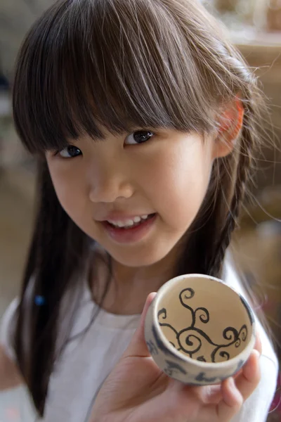 Kleines asiatisches Mädchen zeigt ihre handgefertigte Schale aus Ton — Stockfoto