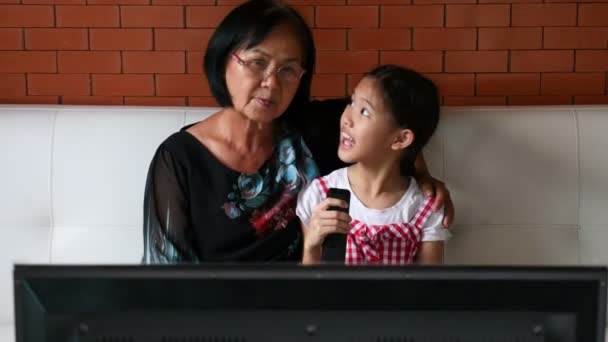 4k: ázsiai vezető nő a kislány néz Tv, kanapé, Tilt megjelöl szemcsésedik — Stock videók