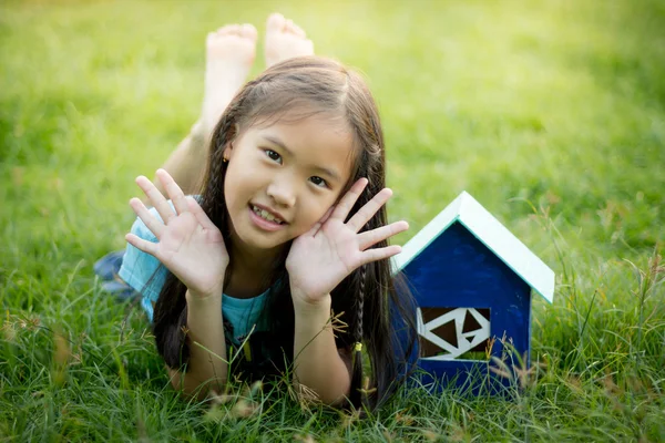 Kleines asiatisches Kind liegt mit Hausspielzeug im Gras — Stockfoto