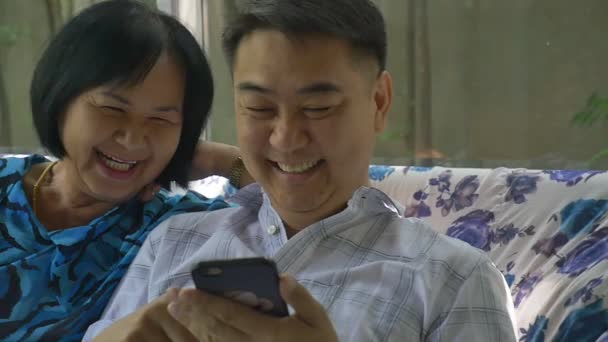 Азиатская старшая женщина и азиатский мужчина используют смартфон вместе — стоковое видео