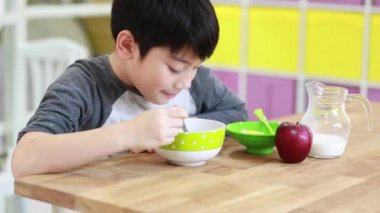 Küçük Asyalı çocuk gülümsemek yüz ile süt ile tahıl yemek