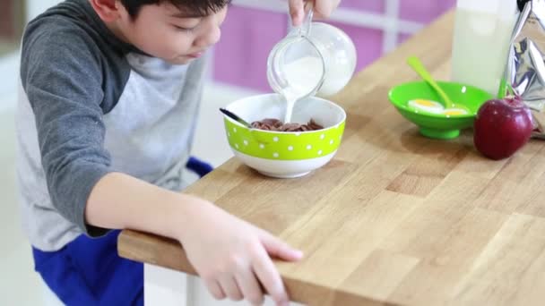 Küçük Asyalı çocuk gülümsemek yüz ile süt ile tahıl yemek — Stok video